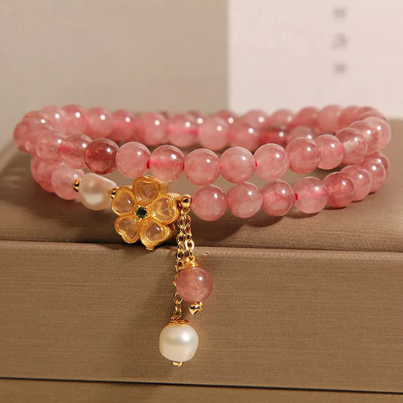 Close-up of a women's bracelet with a strawberry quartz four-leaf clover charm on an alloy chain.