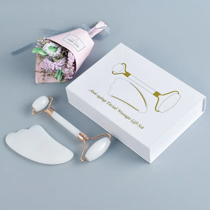 White jade double-headed facial roller and scraping board set on a flat surface.