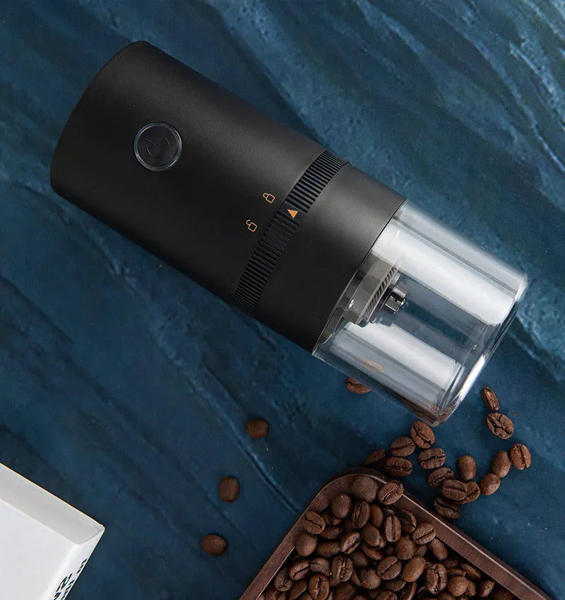 Black portable electric coffee grinder with transparent chamber showing coffee beans, USB-C charging port visible