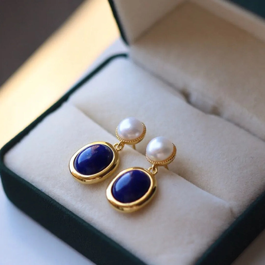 A pair of simple sterling silver drop earrings with blue lapis lazuli pearls and an auspicious pattern.
