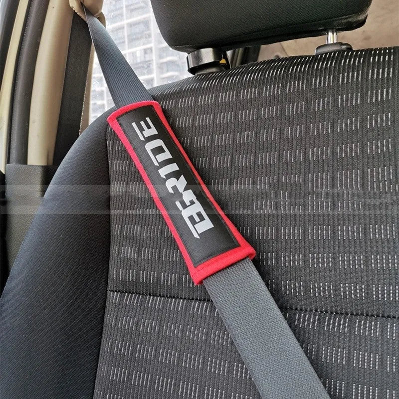 Pair of black car safety belt shoulder pads showing sponge cloth padding and embroidery detail