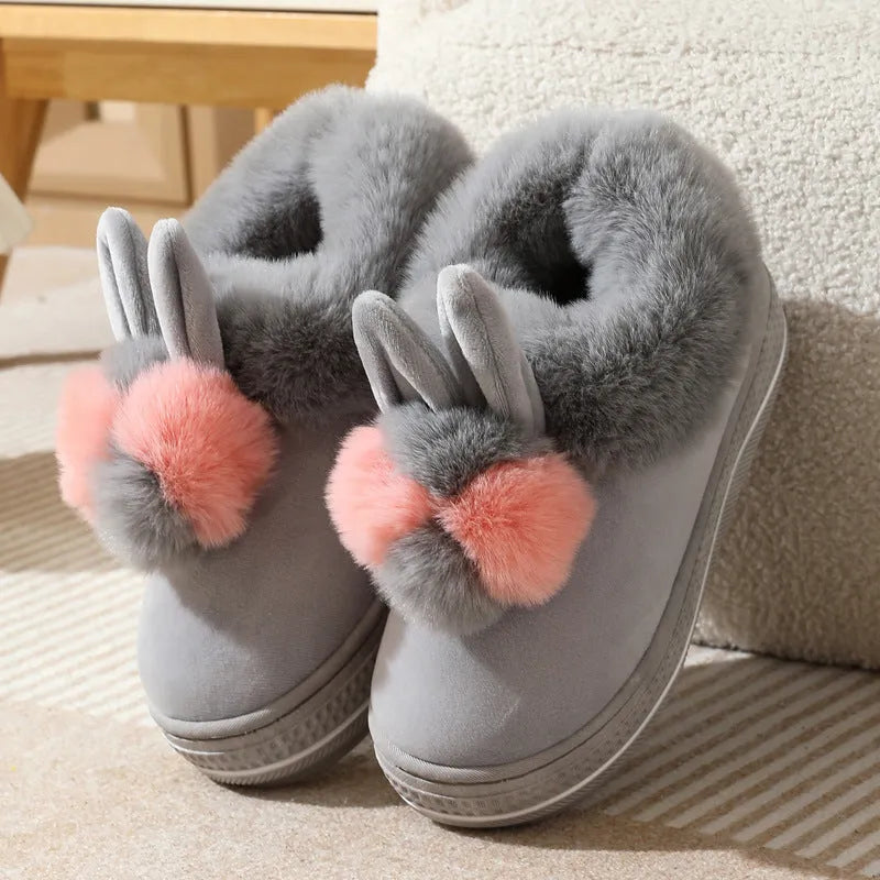 Grey plush high-heel winter slippers with a thick TPR sole on a wooden floor.