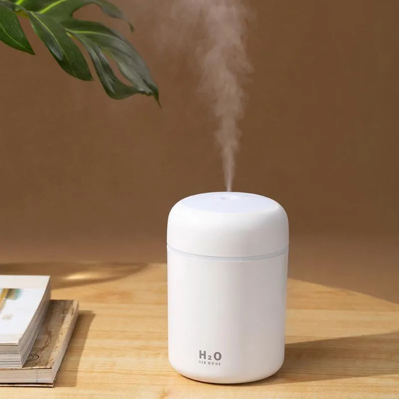 Pink, white, and navy blue USB-powered mini desktop humidifier with water tank and mist spray.