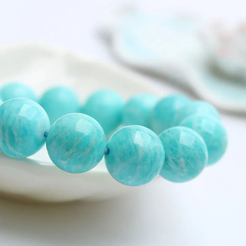 Blue-green amazonite gemstone bracelet with round beads on a black elastic cord.