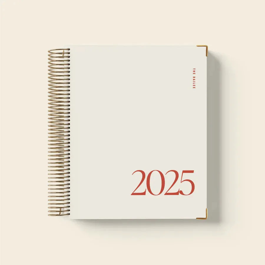 Cherry red A5 daily planner coil notebook open on a weekly view page.