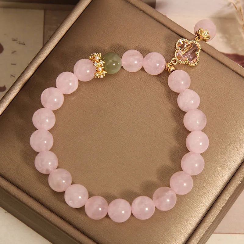Pink crystal bracelet with a four-leaf clover pendant and rhinestone details on an alloy chain.