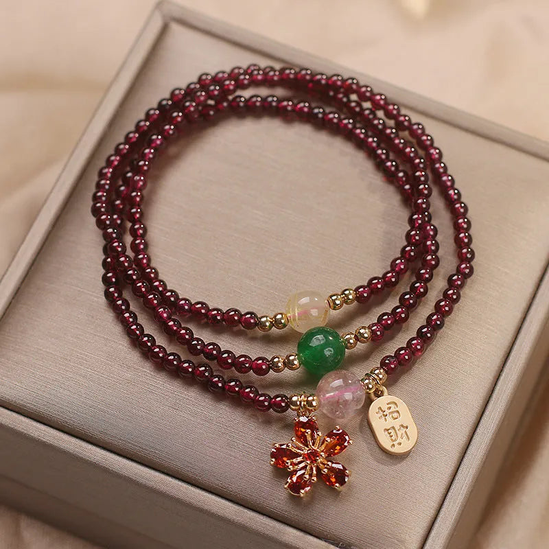 Women's natural crystal bracelet in pomegranate red cherry blossom colour with sequin details on strap.