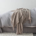 Small grey polyester throw blanket folded on a sofa, measuring 127 by 170 cm.