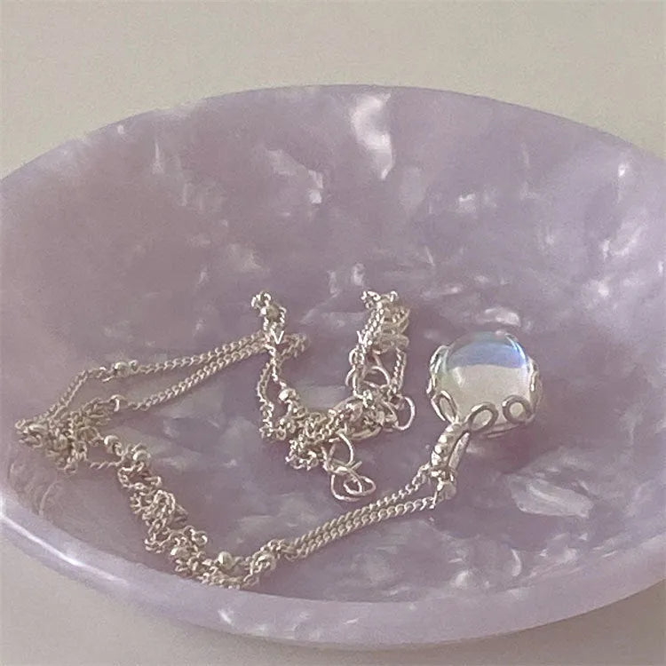 Silver women's necklace with round ornamental stone geometric pendant on a curb chain.