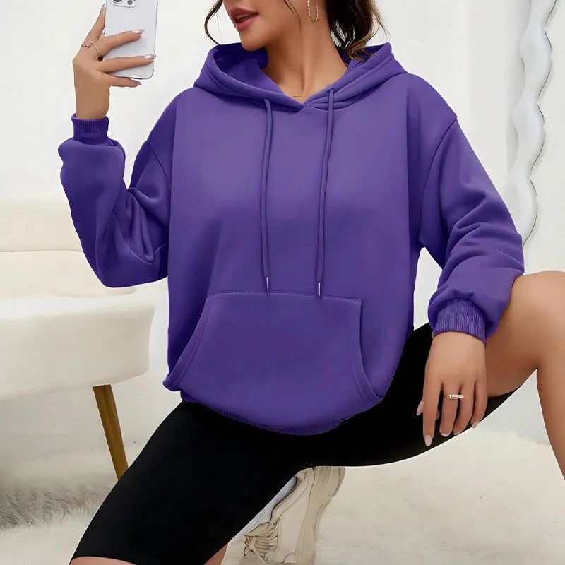 Women's loose fit grey sweatshirt with a drawstring pocket and long sleeves on a hanger.