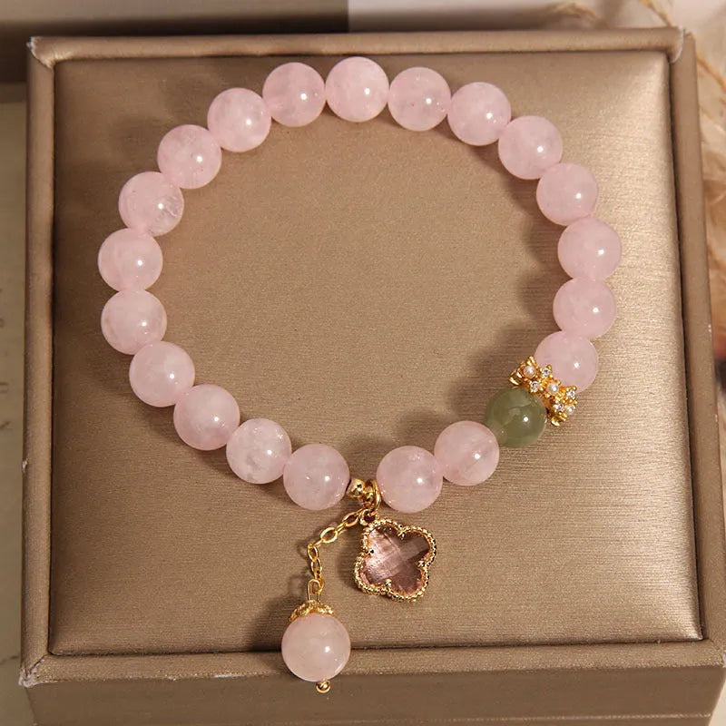 Pink crystal bracelet with a four-leaf clover pendant and rhinestone details on an alloy chain.