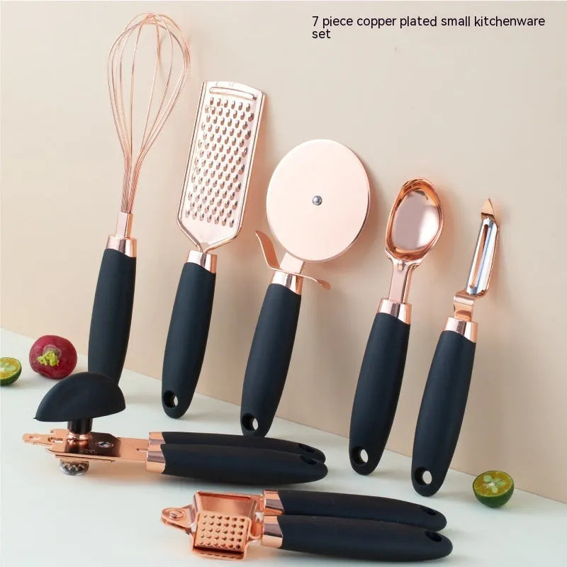 Seven-piece stainless steel kitchen tool set with copper handles on a cutlery rack, in rose gold colour.