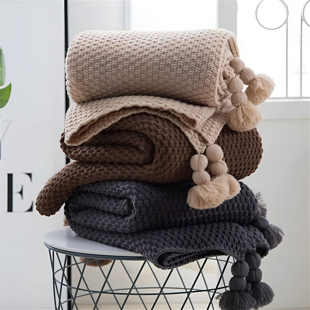 Nordic style fringed acrylic blanket in beige, measuring 130 by 170 centimetres, draped over a sofa.