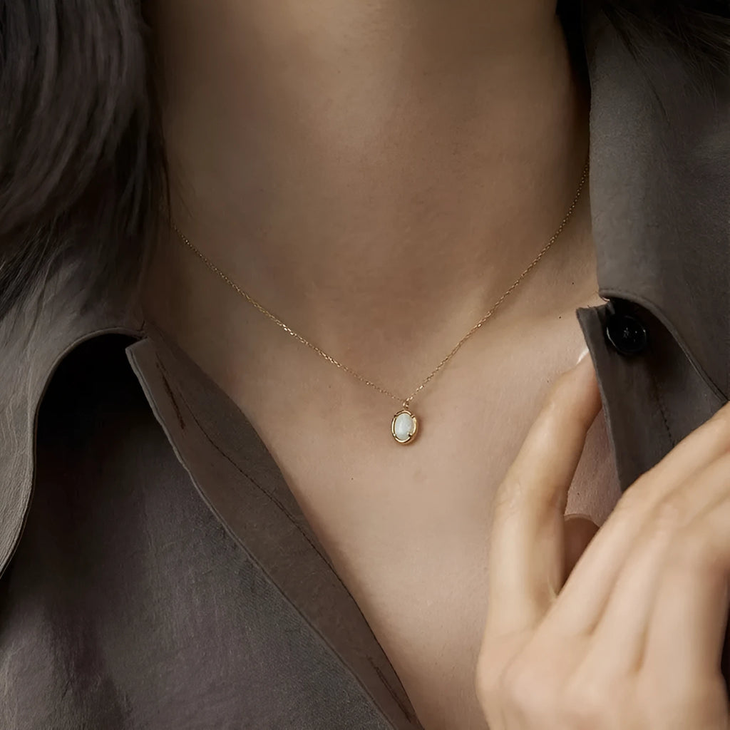 S925 sterling silver necklace with a geometric pendant holding a round jelly opal, plated in gold.