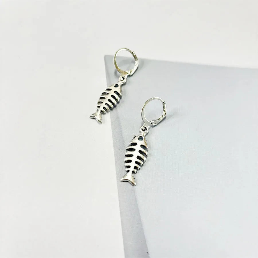 Women's fishbone pendant necklace and matching earrings set with adjustable chain on retro background