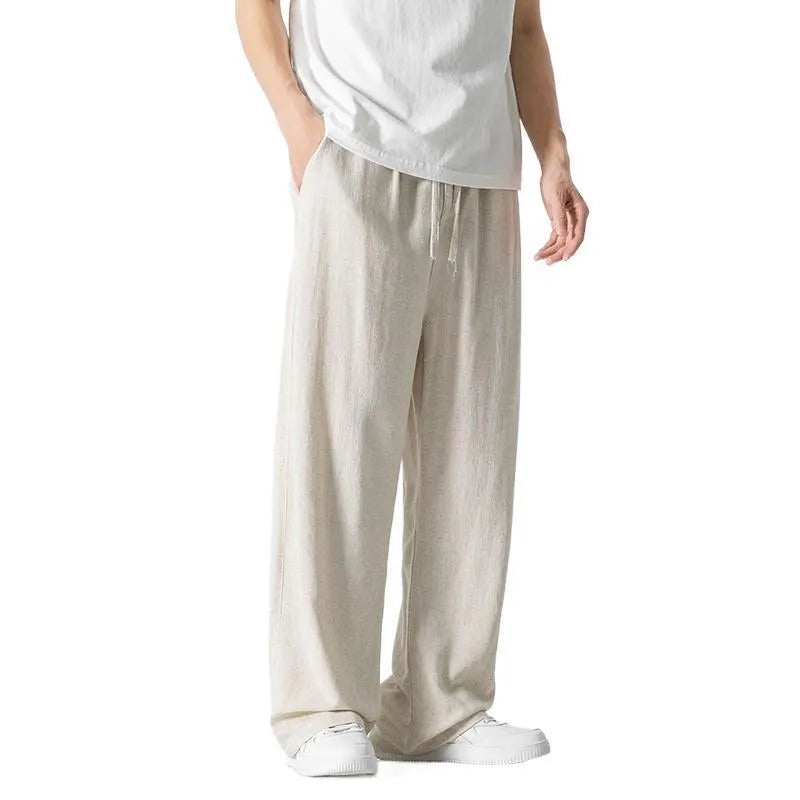 Man wearing beige straight-leg cropped linen-style trousers with a drawstring waist.