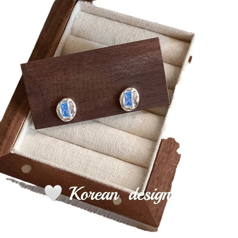 S925 sterling silver earrings with geometric heart-wrapped design and oval blue diamond elements