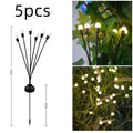 Solar-powered LED pneumatic firefly ground stake light with multiple heads on a grassy lawn.