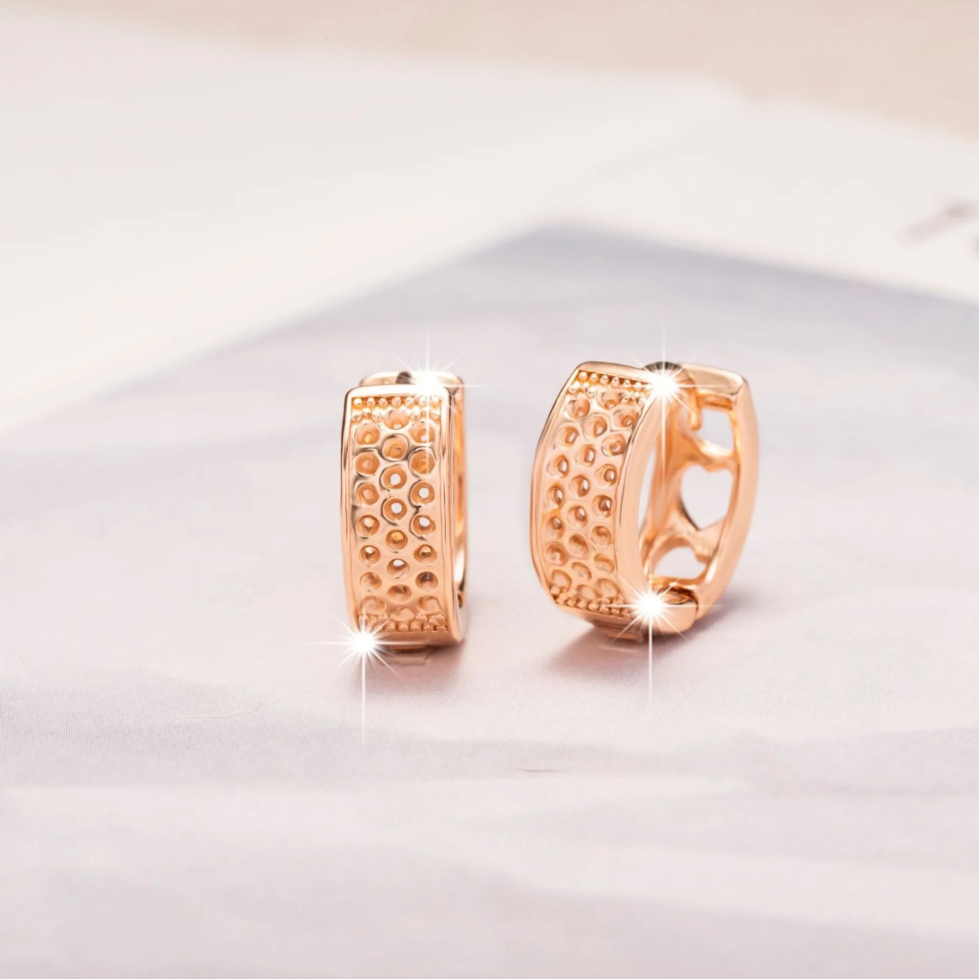 Rose gold women's earrings with three hollowed heart charms on a circular setting.