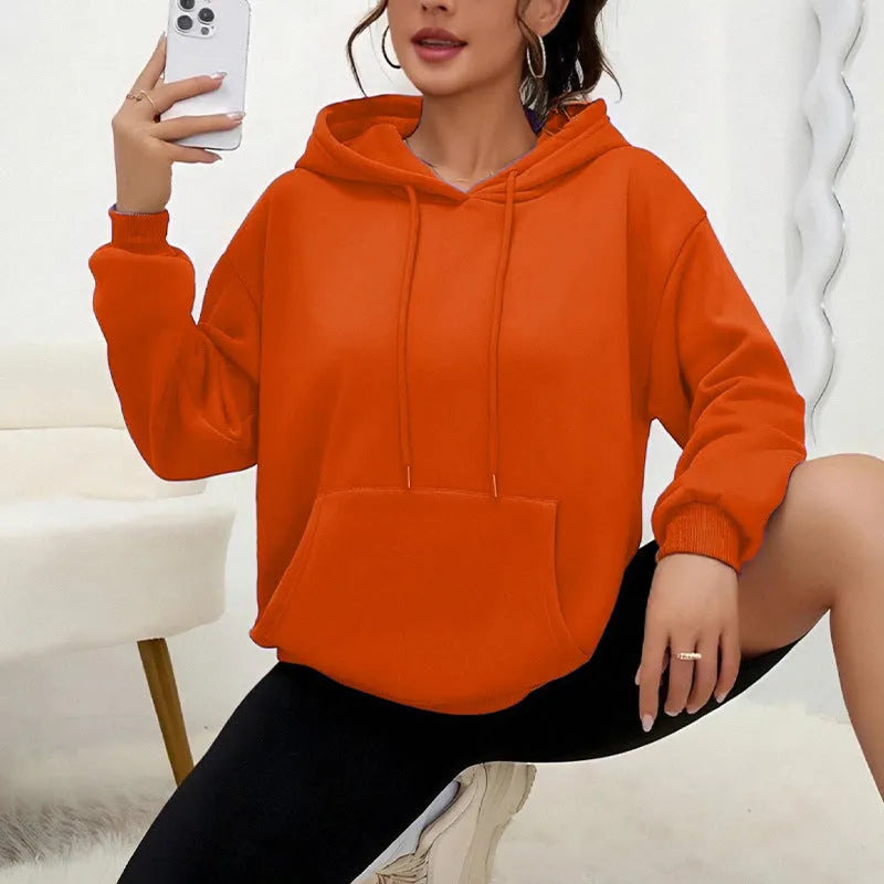 Women's loose fit grey sweatshirt with a drawstring pocket and long sleeves on a hanger.