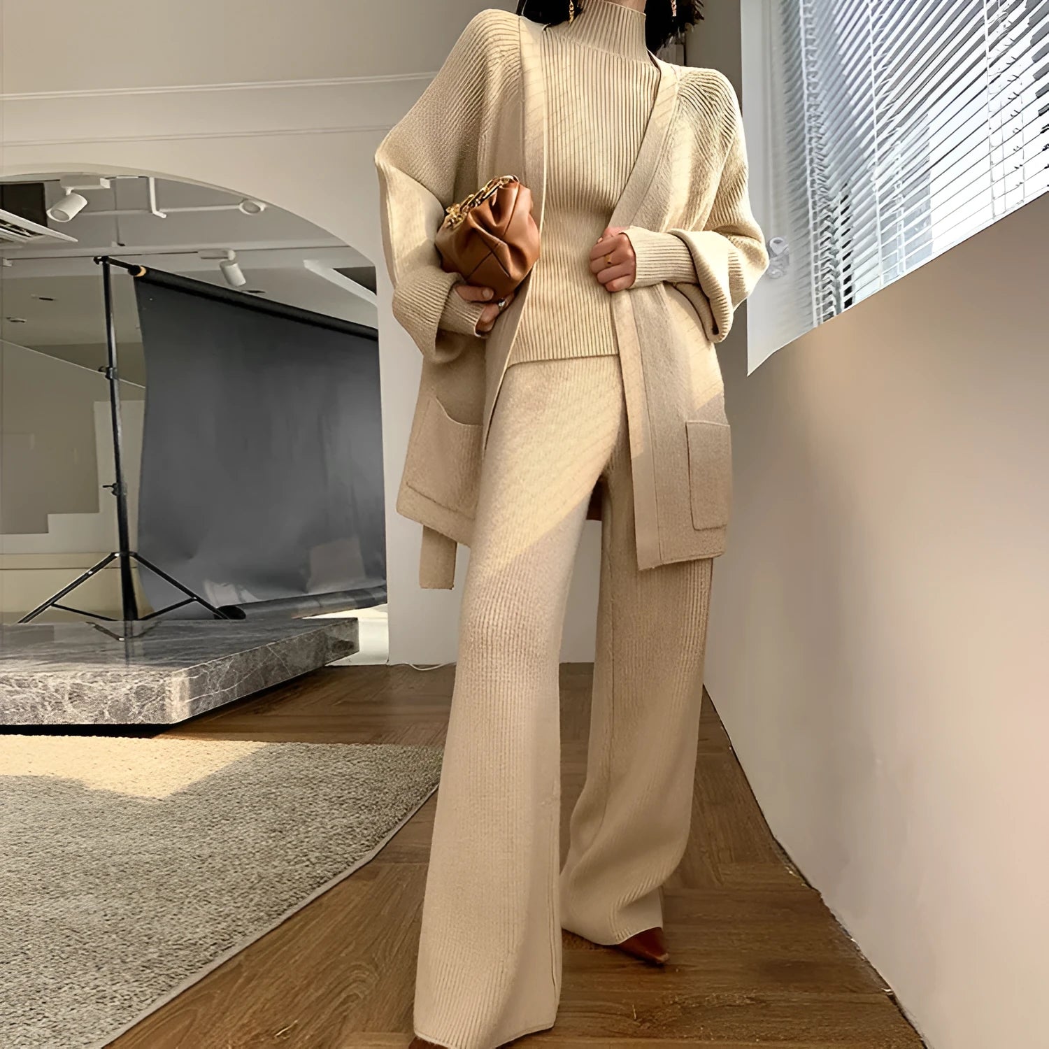 Women's apricot knitted wide-leg pants, sweater, and cardigan three-piece set with leather stitching detail.