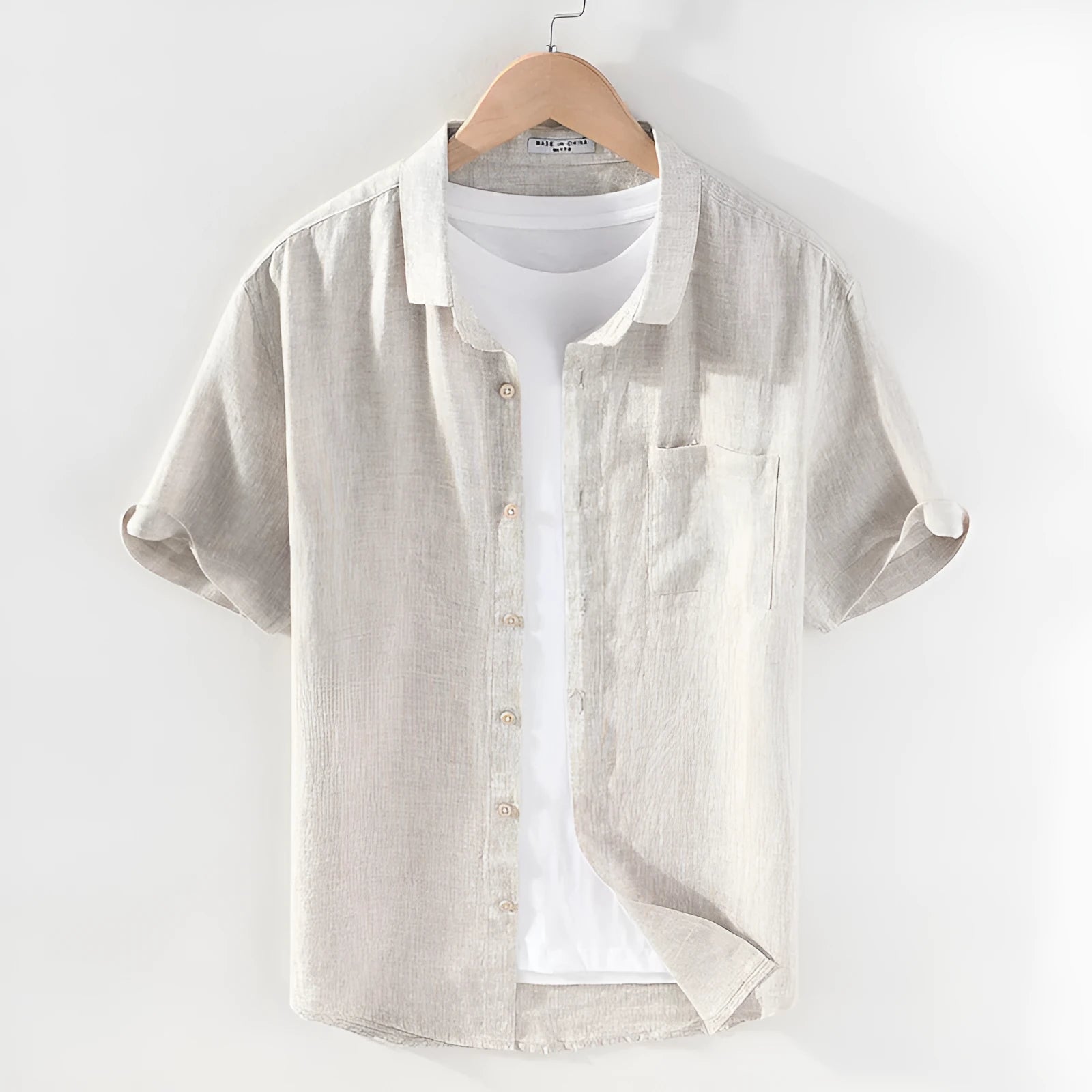 Man wearing a raw jute coloured short sleeve linen shirt with a square collar.