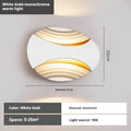 A modern aluminium wall lamp mounted beside a bed, showcasing its minimalist design.