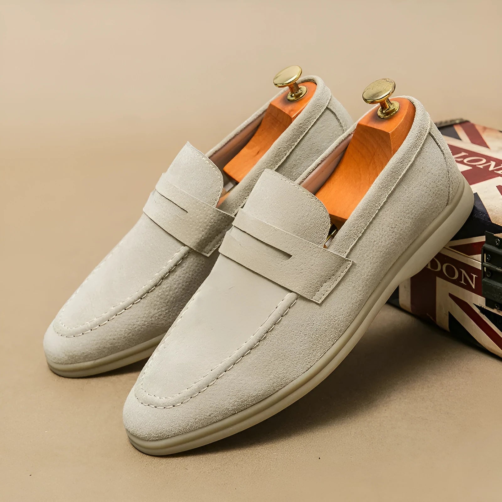 Men's beige leather slip-on casual shoes with a round toe and rubber sole on a white background.