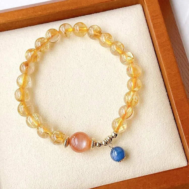 Gold rutilated quartz sunstone bracelet with diamond shapes and round beads on female wrist