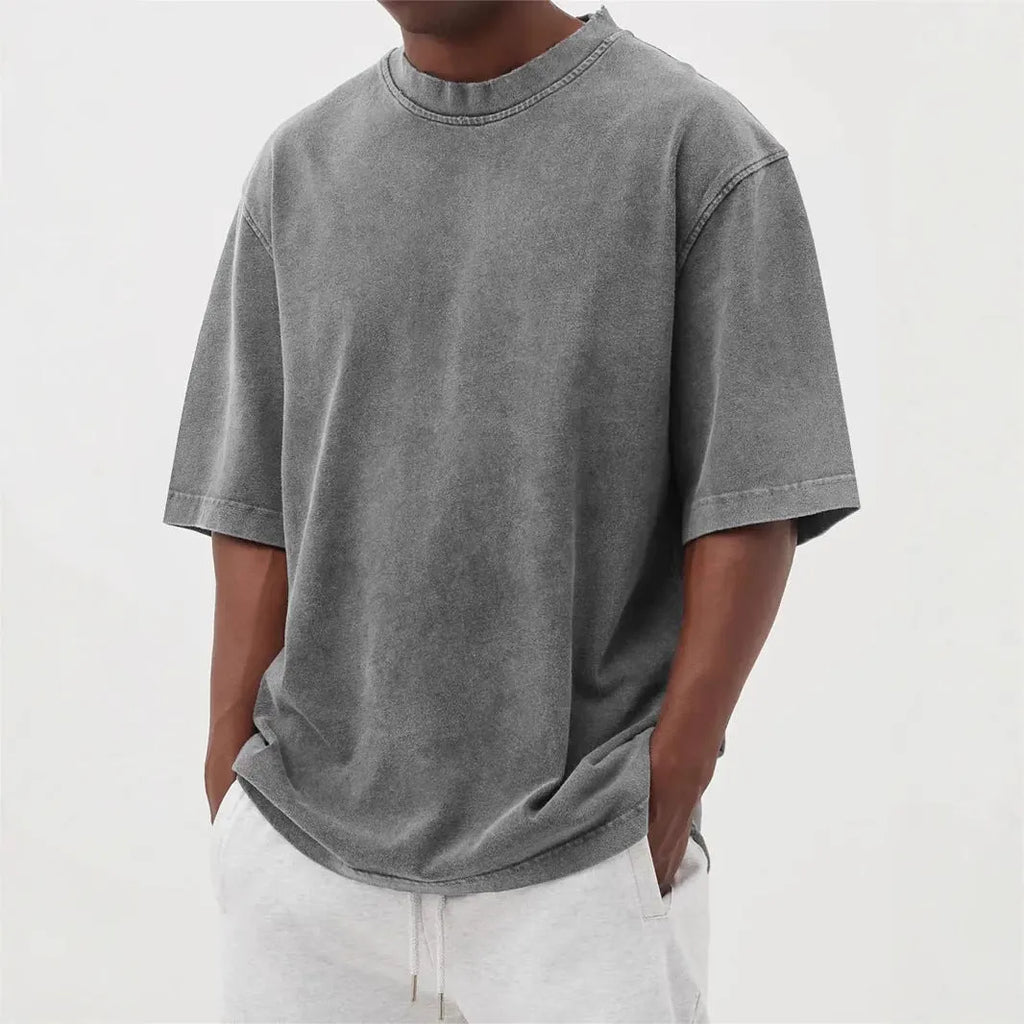 Man wearing a loose fit stone washed distressed t-shirt in a solid colour, showing short sleeves and casual styling.