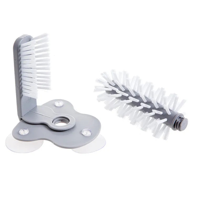 Grey 2-in-1 cup scrubber with double-sided bristles and three suction cups on a white surface