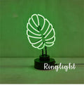 Minimalist white bamboo-shaped desk lamp emitting a soft green light, shown on a table.