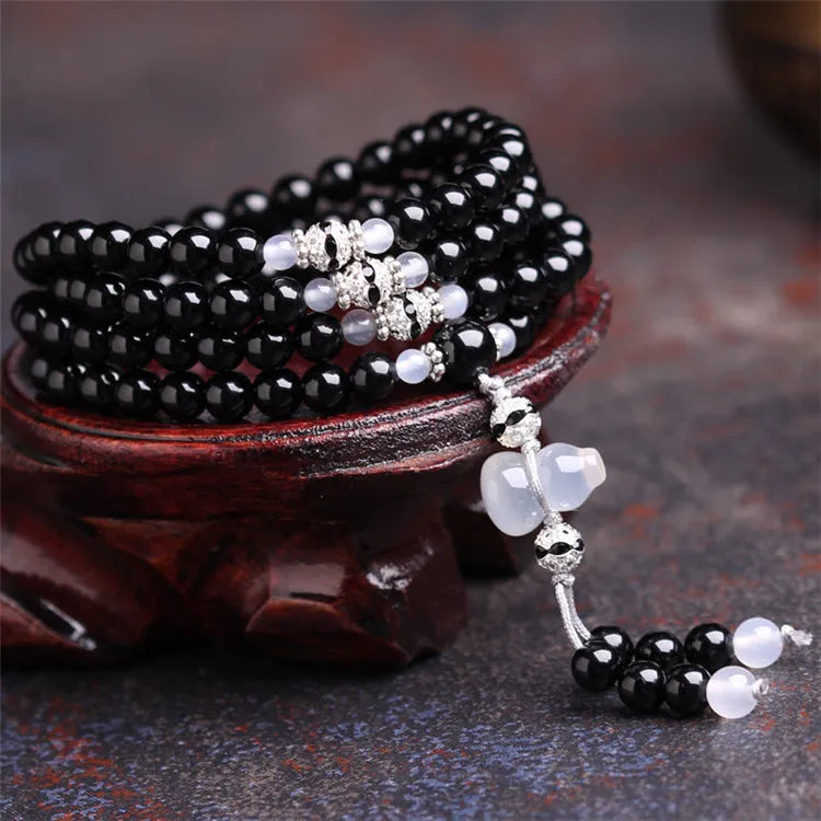 Black agate bracelet with 108 geometric beads on a wrist.