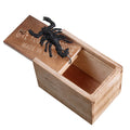 Wooden prank scare box open showing a lifelike spider figurine on a spring, next to the box lid.