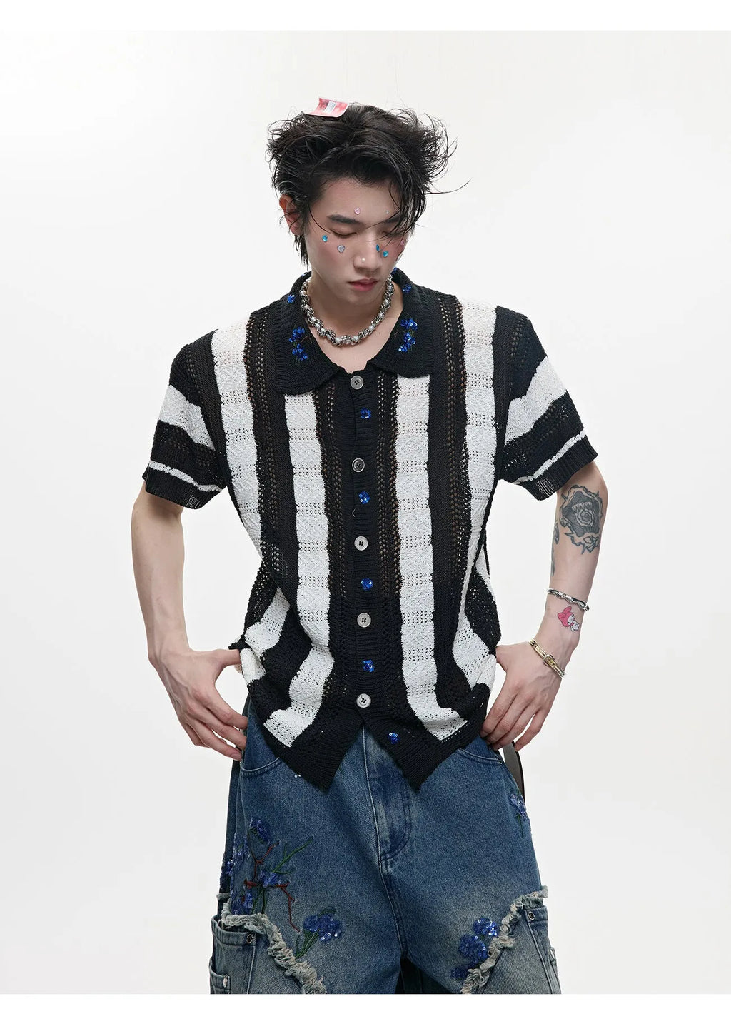 Man wearing a red and black patchwork striped knitted short sleeve shirt with a loose fit.