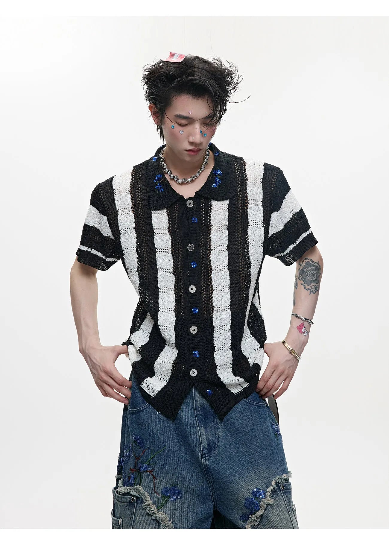 Man wearing a red and black patchwork striped knitted short sleeve shirt with a loose fit.