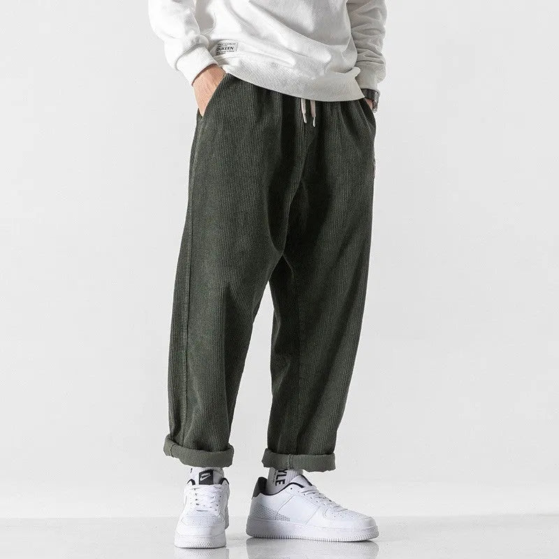 Men's loose straight corduroy sports trousers in Army Green on a grey background.