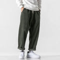 Men's loose straight corduroy sports trousers in Army Green on a grey background.