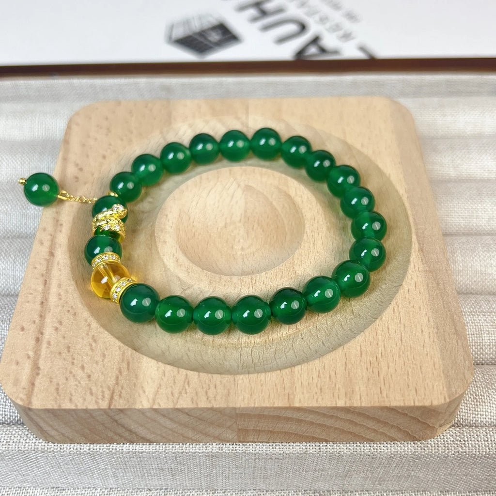 Green and red agate stone bead wealth snake bracelet with copper details on a wrist.