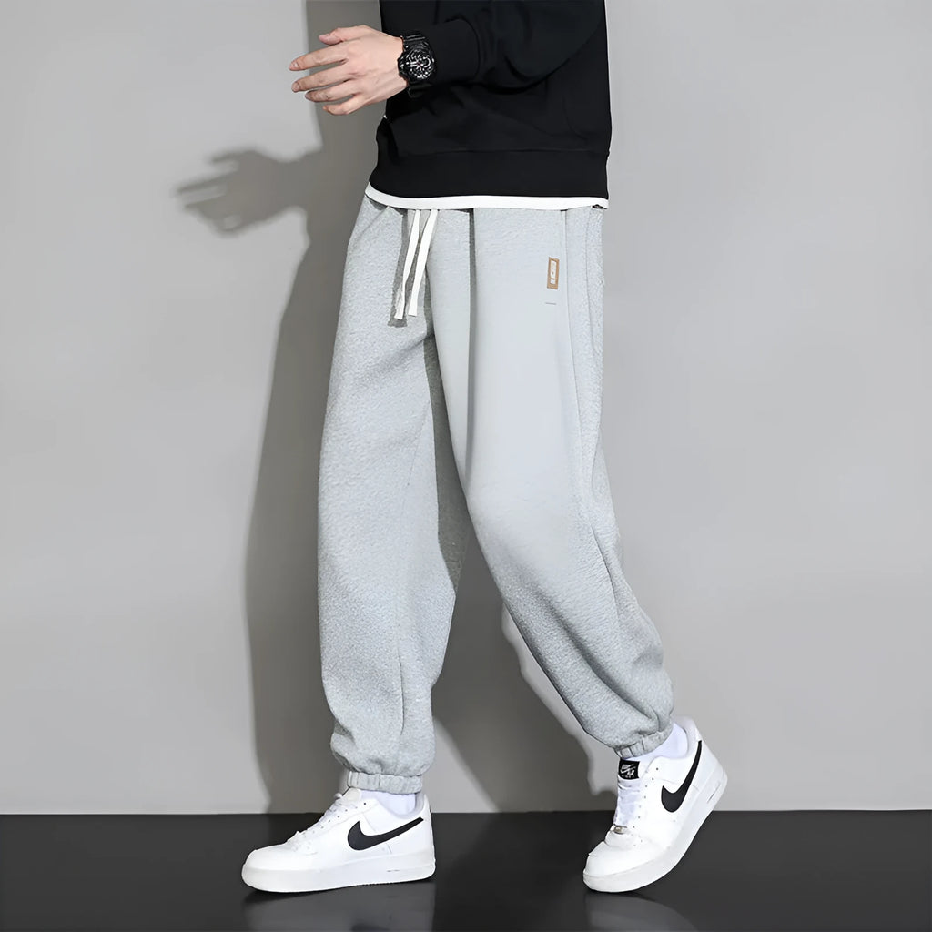 Men's loose grey casual sports trousers with drawstring waist on a plain background
