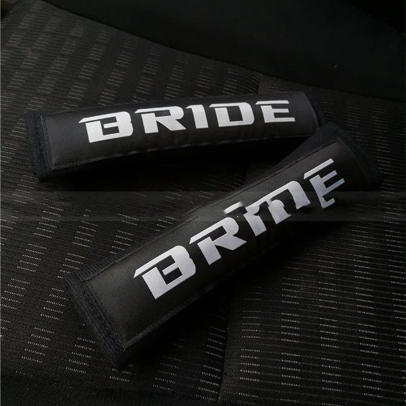 Pair of black car safety belt shoulder pads showing sponge cloth padding and embroidery detail