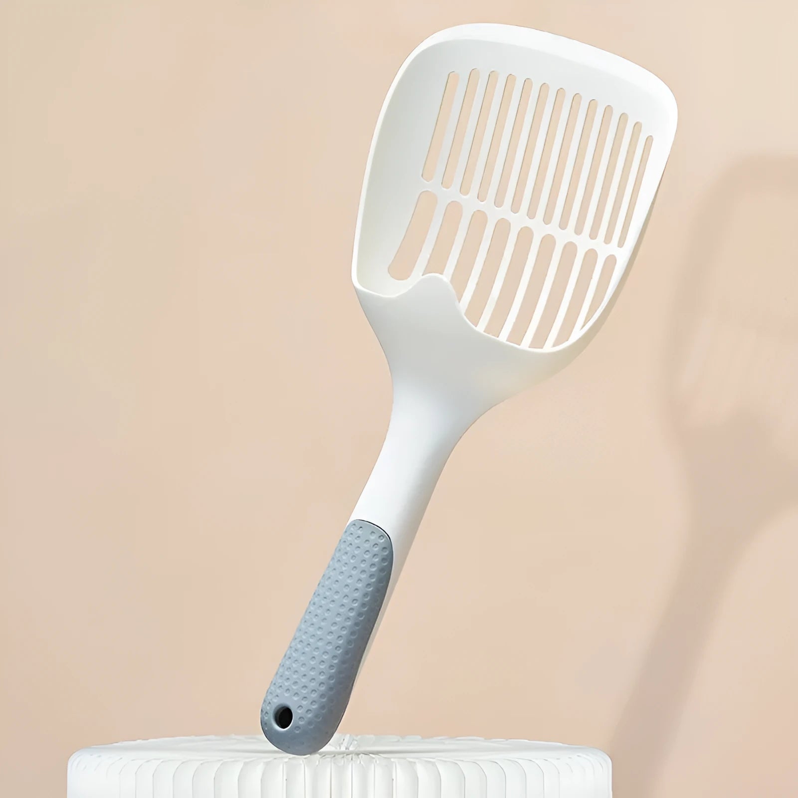White plastic cat litter scoop with a self-cleaning base on a white background.