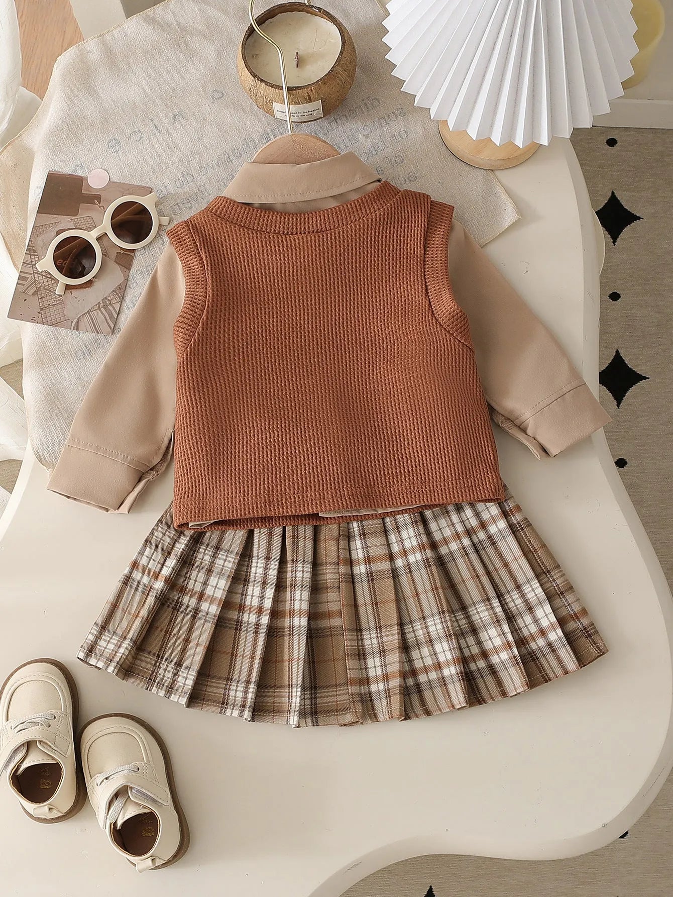 Girls' light brown plaid three-piece set with top, knitted vest, and pleated skirt on white background