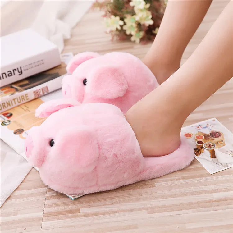 Pink pig-shaped plush floor slippers on a white background.