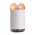 White desktop ultrasonic humidifier with crystal salt stone and LED lamp showing side view on table