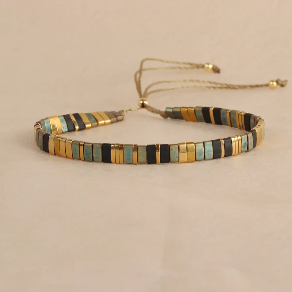 Geometric glass beaded bracelet in milky white, black, green, blue, or red on a plain background.