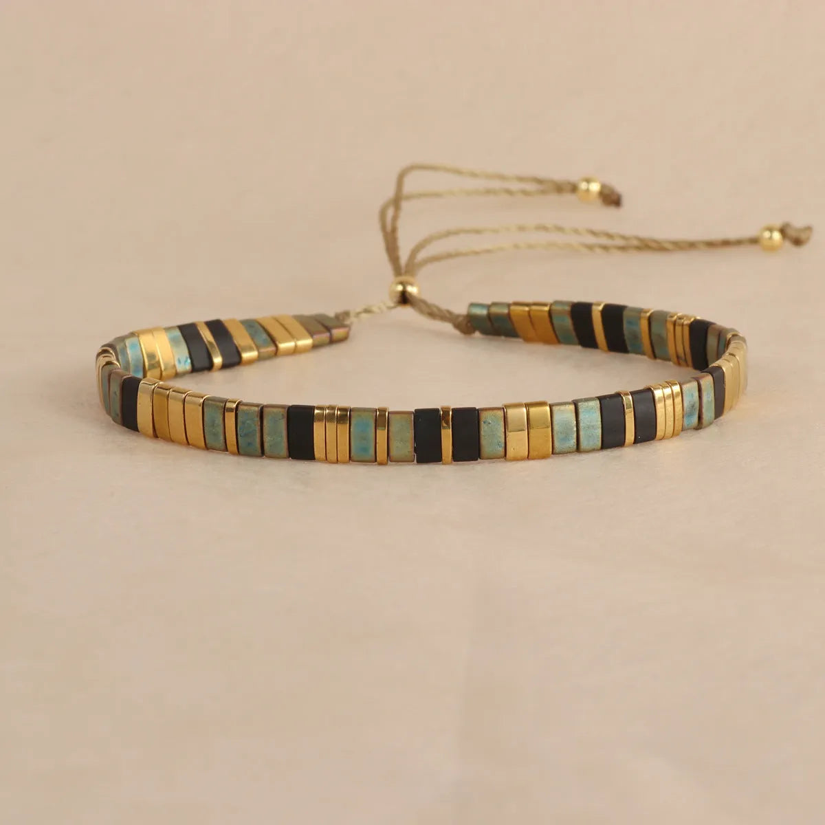 Geometric glass beaded bracelet in milky white, black, green, blue, or red on a plain background.