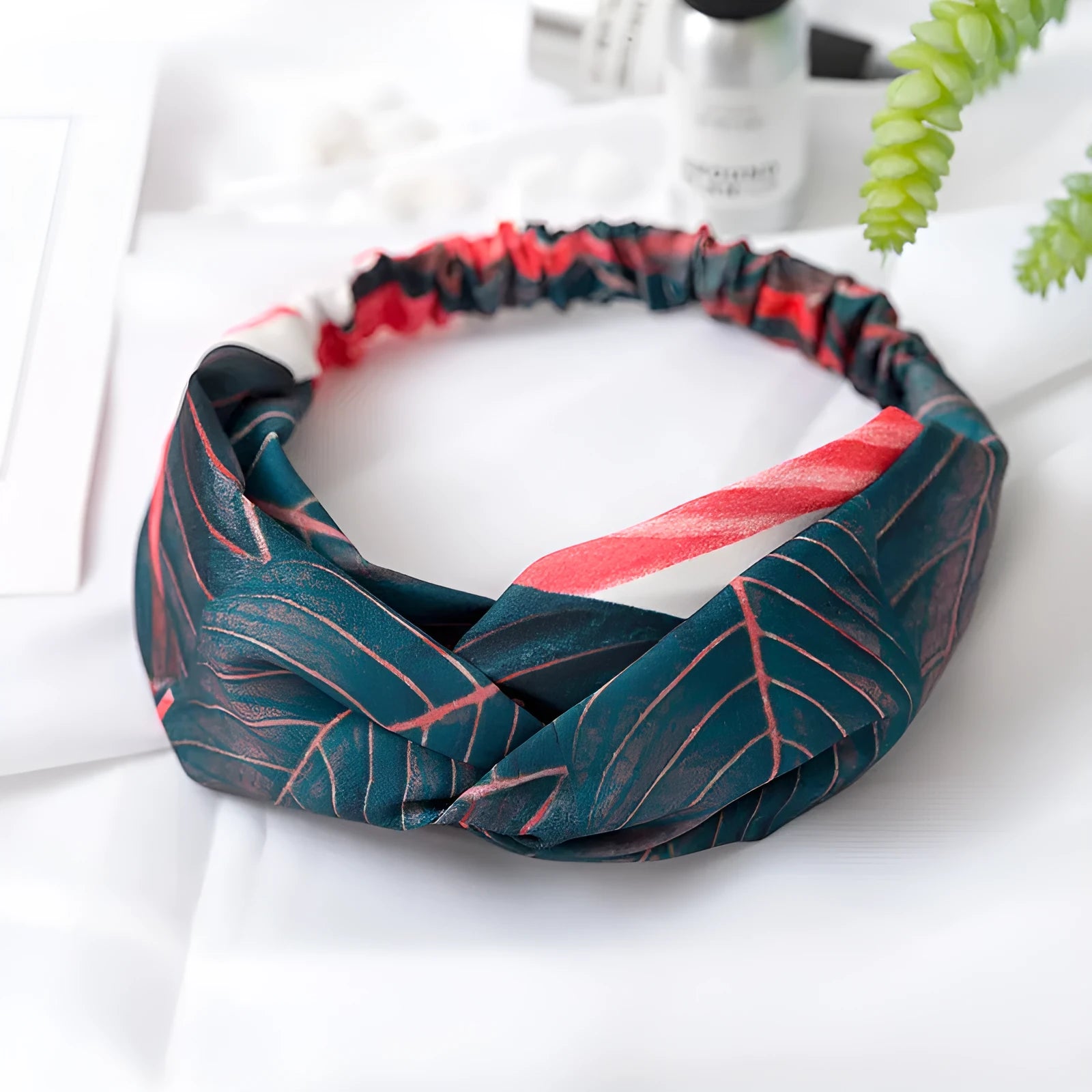 Red cloth headband with banana leaf pattern, showing wide band and elastic back.