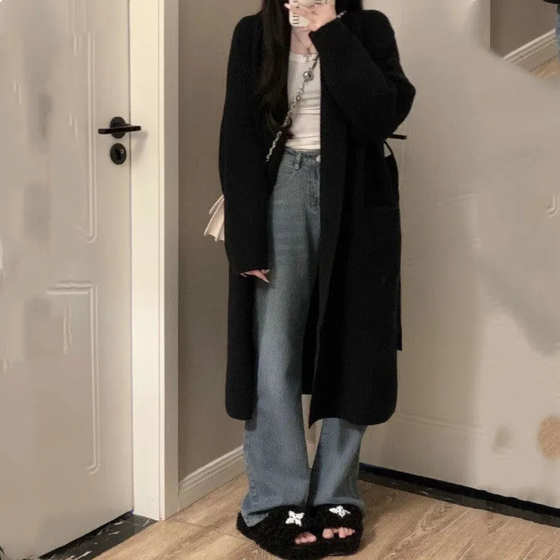 A woman wearing a loose, dark grey knitted chenille cardigan with a 3D-effect texture.