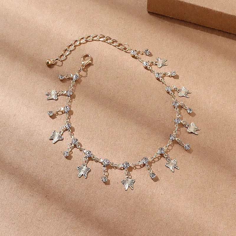 Gold alloy butterfly tassel anklet with colourful floral and leaf design on foot for summer beach wear